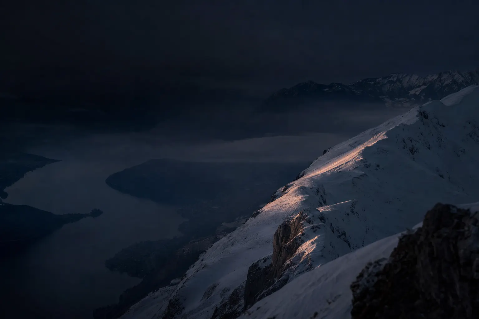Massif alpin enneigé au-dessus d'Annecy, lumière rasante de fin de journée